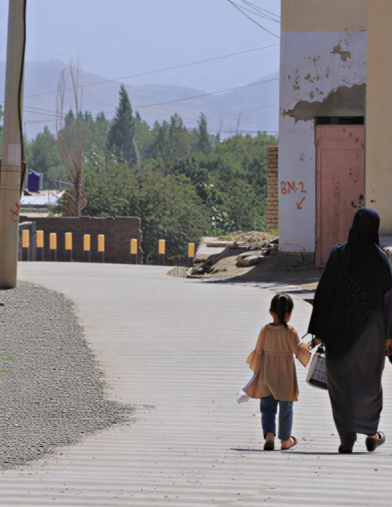 امرأة في أفغانستان تمسك بأيدي ابنها وبناتها.