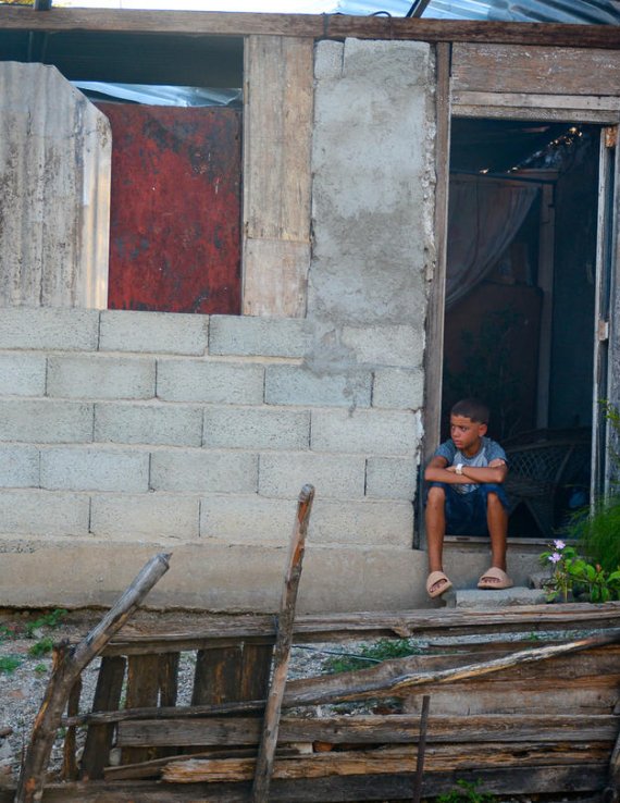 Un niño está sentado frente a su casa en Cuba.