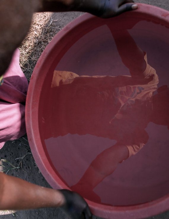 A child in South Sudan sees his reflection in a bucket of water.