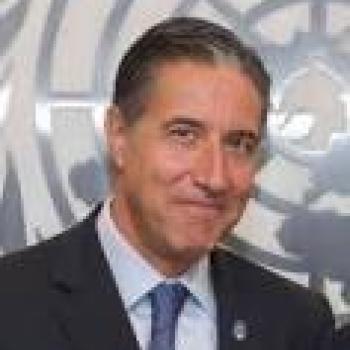 صورة لأوسكار فرنانديز تارانكو مبتسما أمام شعار كبير للأمم المتحدة.