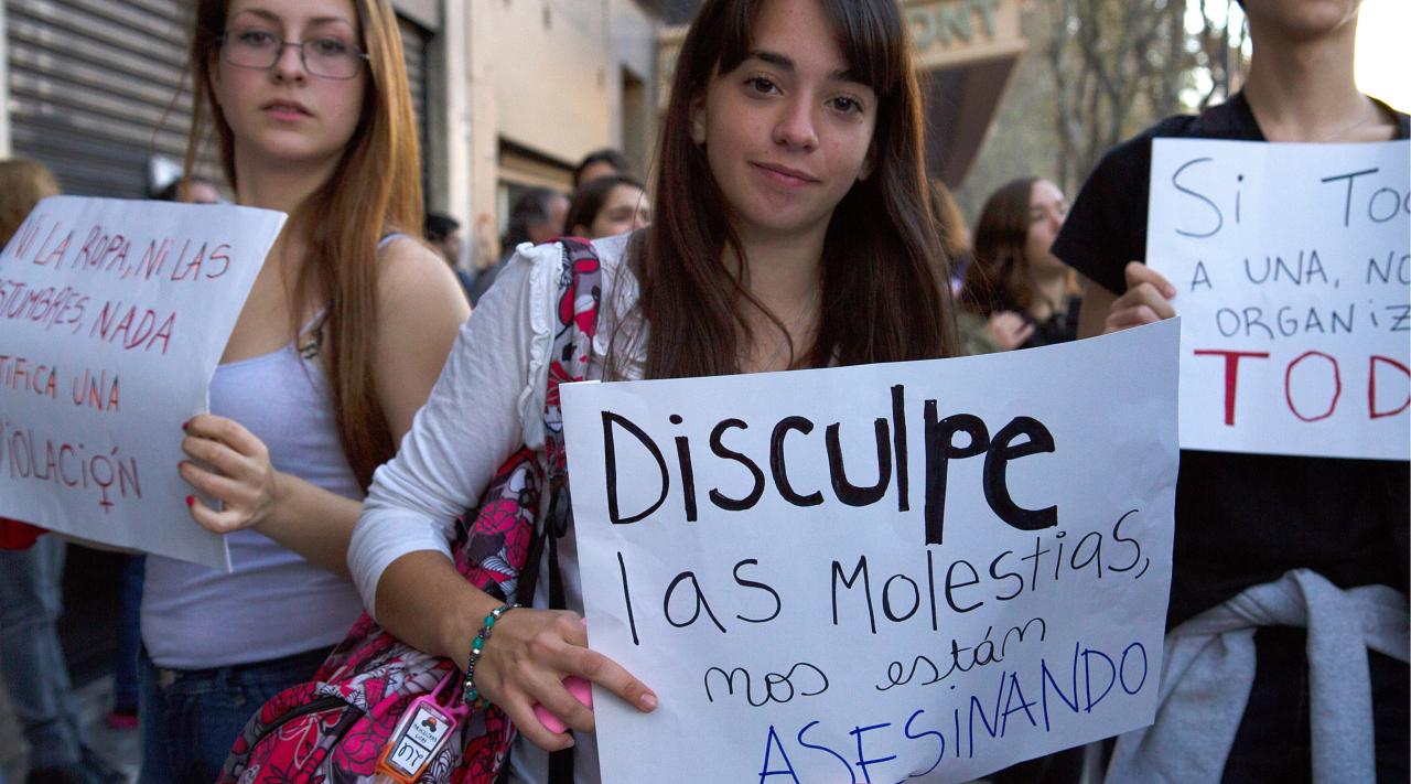 Youth protestors hold up signs as they face the camera. 