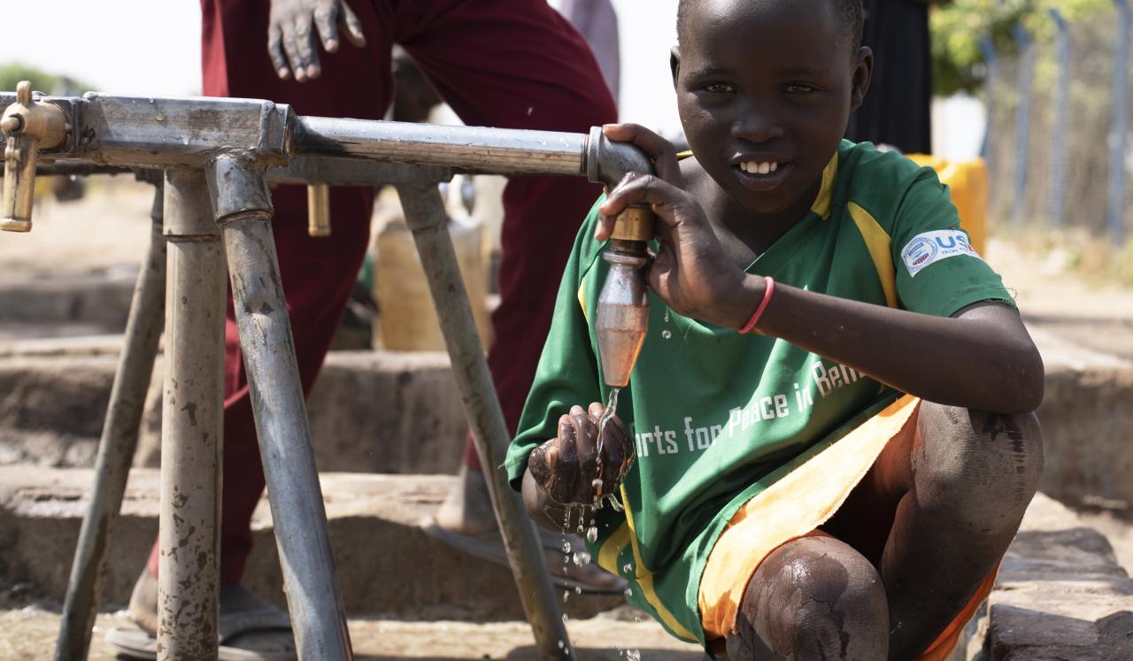 Fuera de la planta de tratamiento de agua en Bentiu, los niños beben de un quiosco de agua suministrado por la planta de tratamiento de agua.