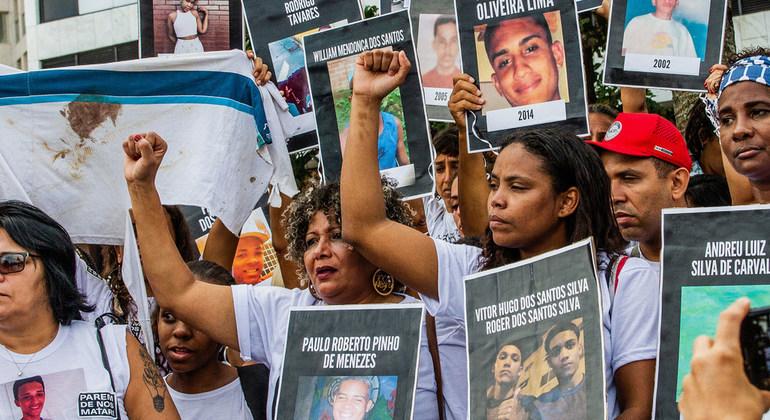 Image shows a group of men and women holding signs of youth who have passed.
