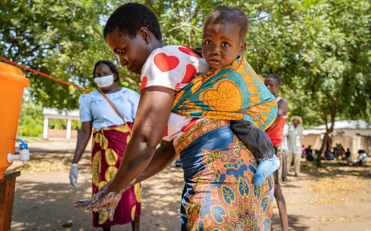 Alinafe Nhlane, a subsistence farmer, is shown washing her hands with her baby.