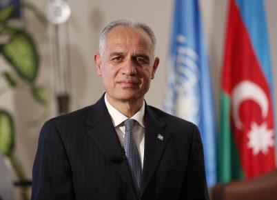 Foto oficial del Coordinador Residente, Ghulam M, Isaczai, delante de la bandera de la ONU y de Azerbaiyán.