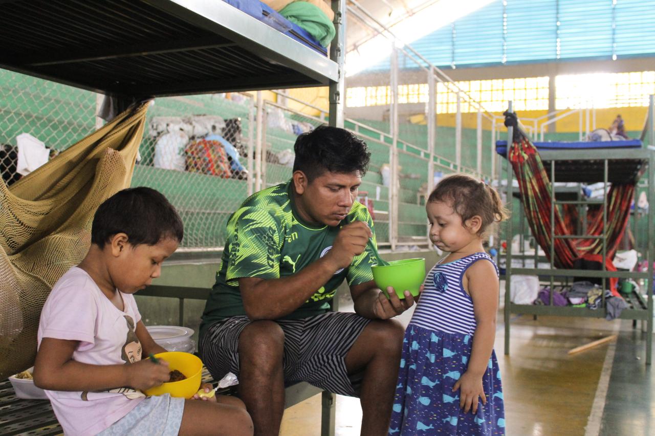 IOM distributed essentials to the shelters in Brazil housing refugees from Venezuela. A family staying at the shelter eat together. 