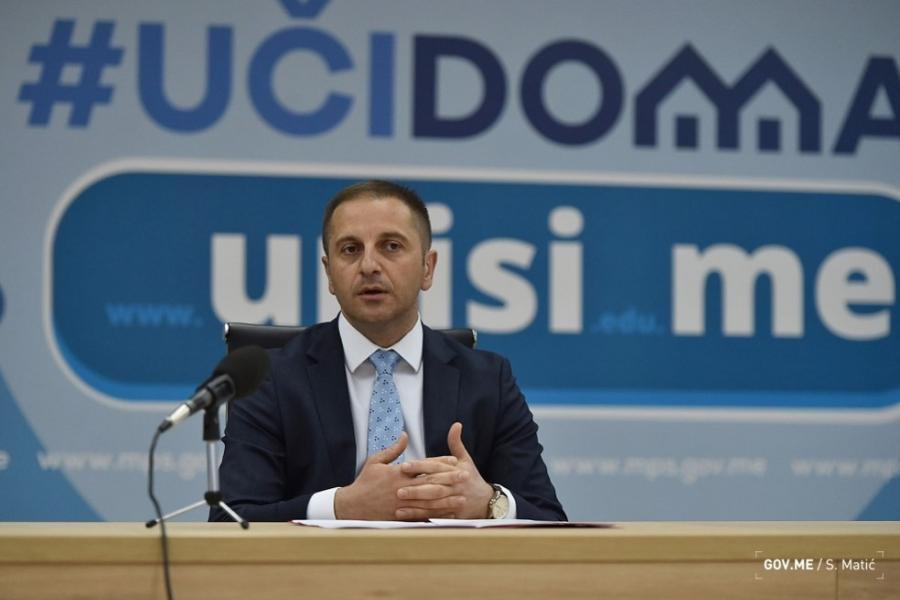 The photo shows the Minister of Education speaking to an audience during a panel discussion.
