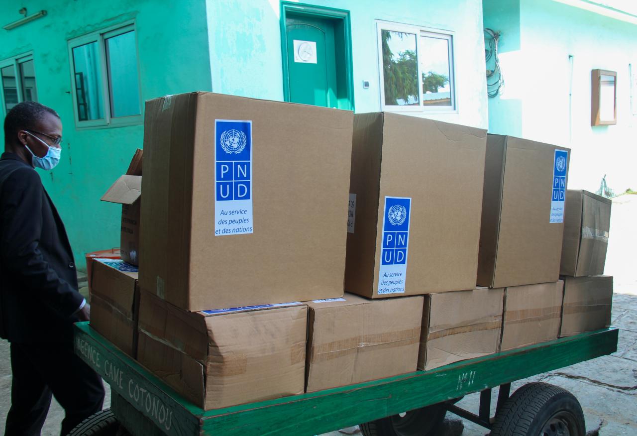 A man stands by a cart full of boxes of lifesaving supplies. 
