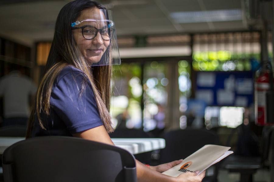 Gabriela smiles proudly at the camera as she holds a folder of material for her clients.