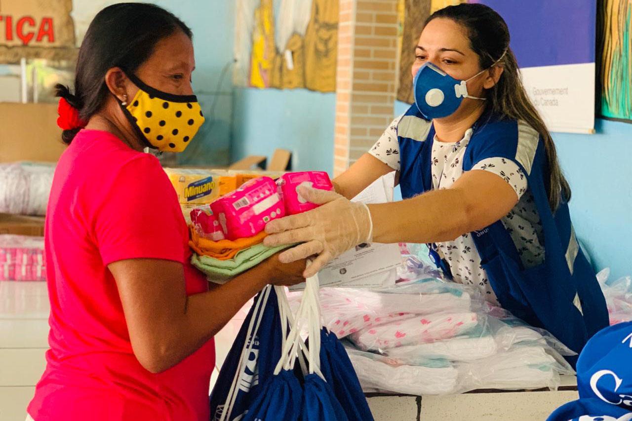 IOM staff hands an indigenous woman essential supplies. 