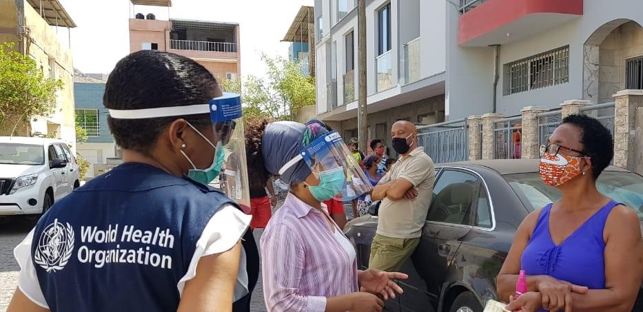 Un miembro del personal de la Organización Mundial de la Salud junto a dos mujeres en un barrio de Cabo Verde.