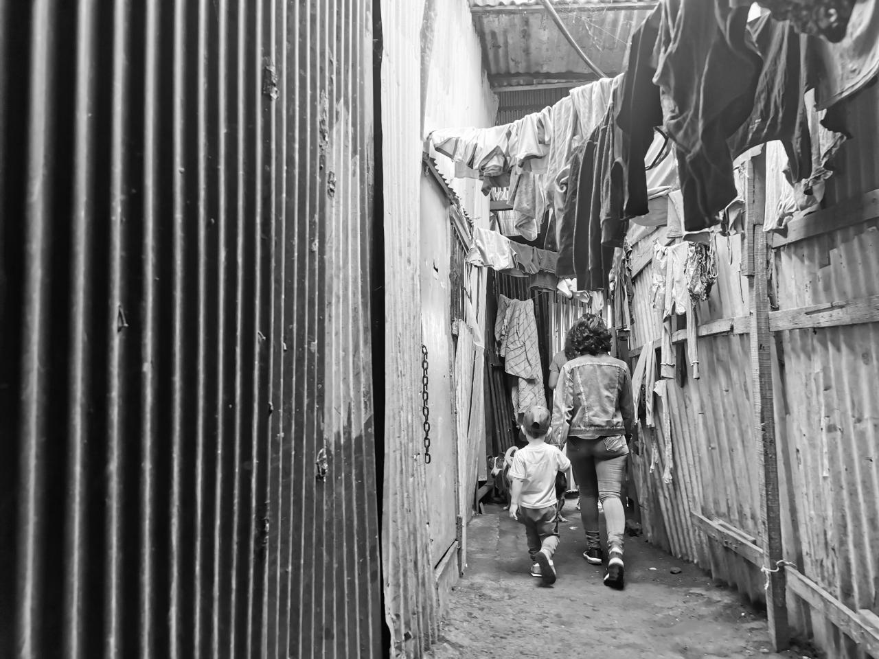 Lilith holds her sons hands as they walk away through a passageway.