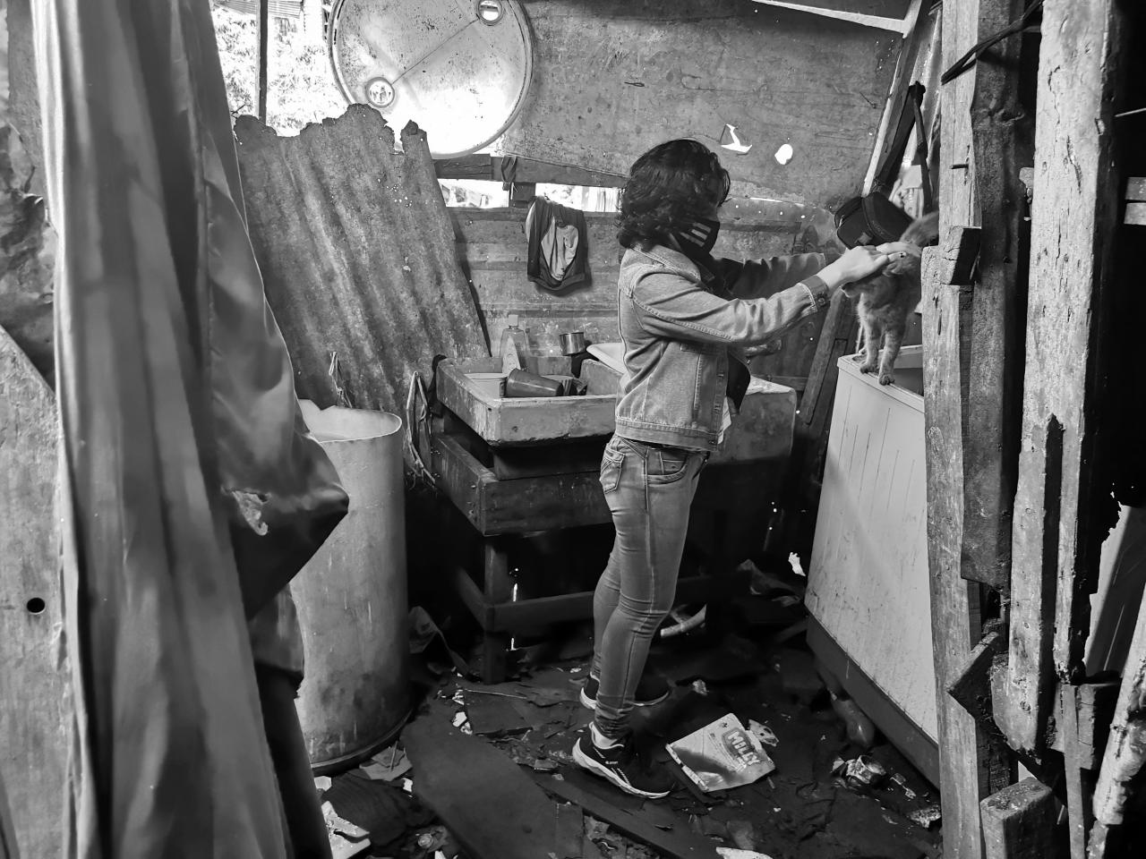 Lilith stands in a makeshift room as she gently pets her cat.