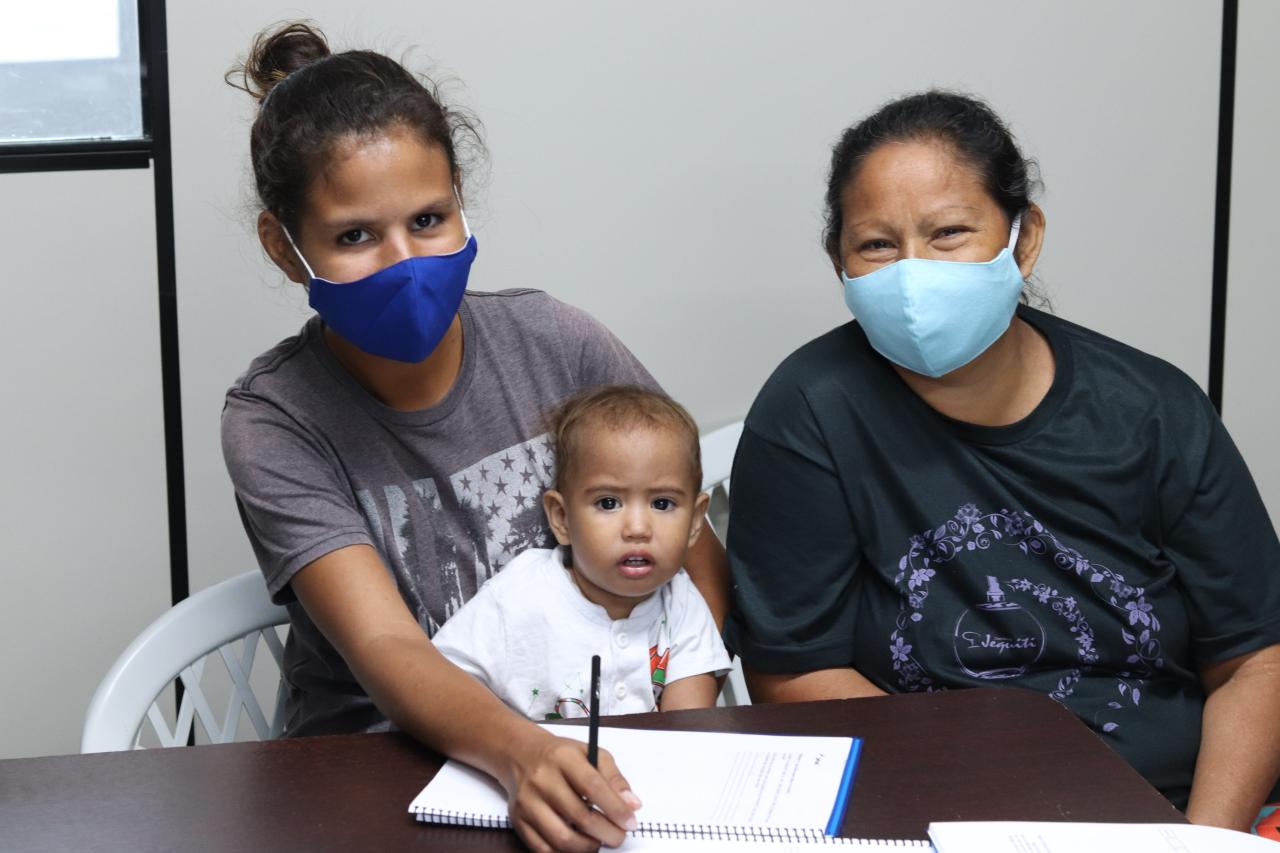 Dashly González, age 21, her mother and baby son smile and sit together during one of the programmes.