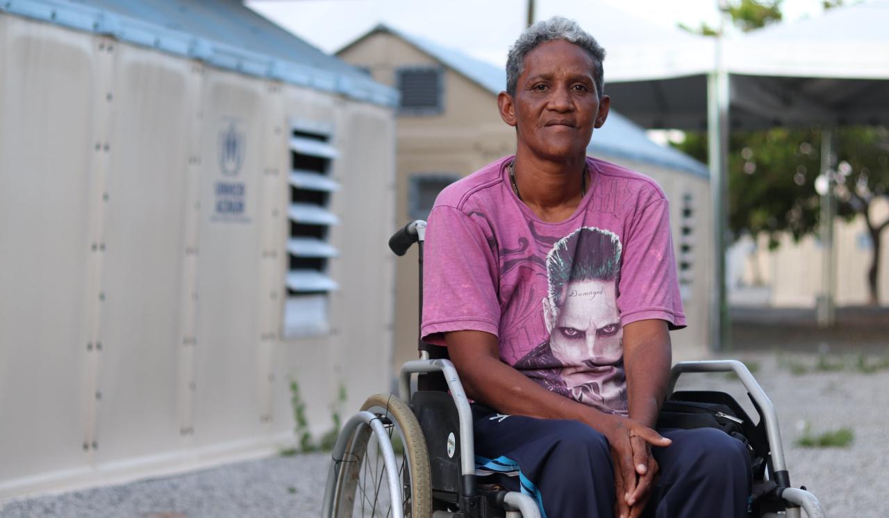 A woman sits in her wheelchair outside the training facility.