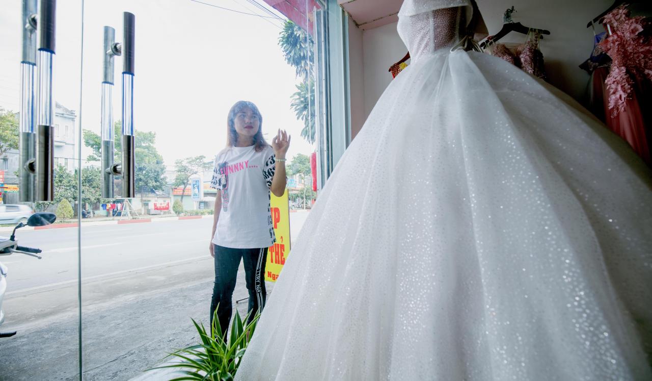 Lo Kim Thuy admira un vestido de novia expuesto en el escaparate de una tienda.