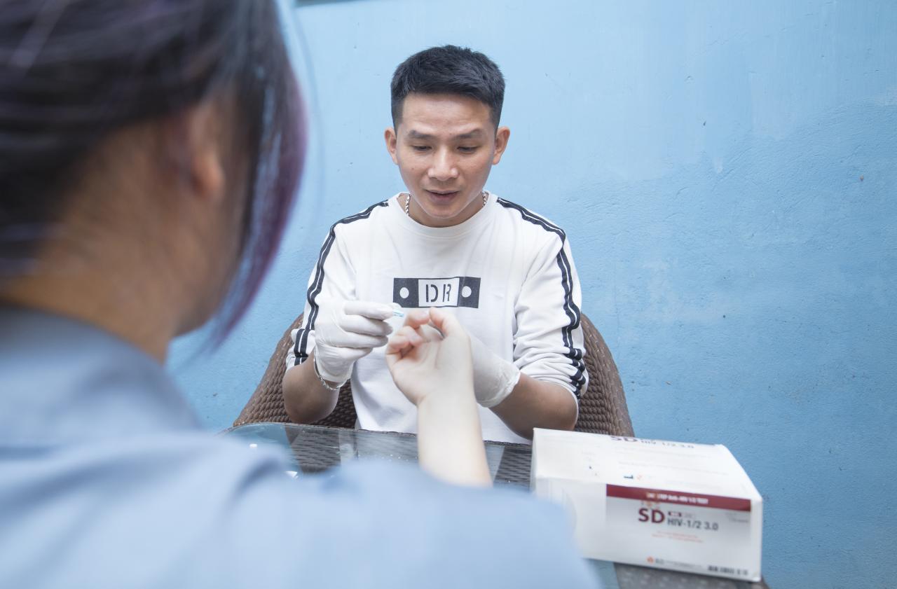Nguyen Trong Hung provides an HIV screening for one of his customers at Hung's coffee shop.