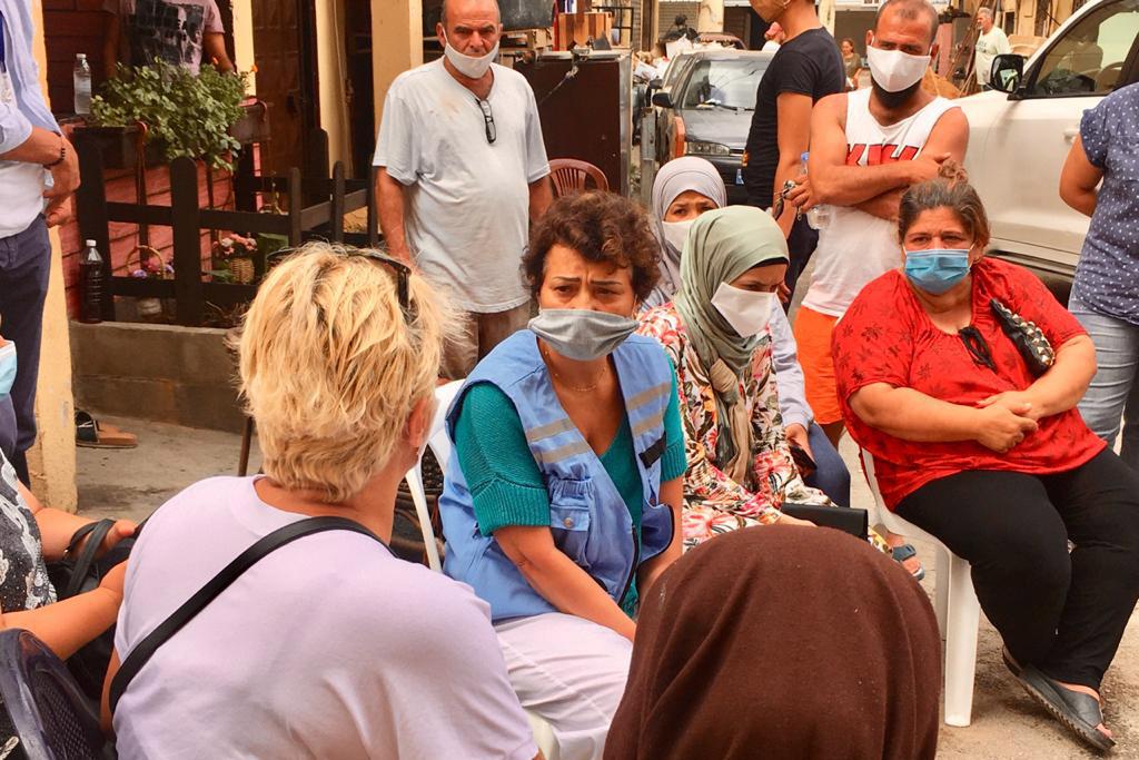 Najat Rochdi sits in between a group of women and men at one of the hardest hit neighbourhoods.