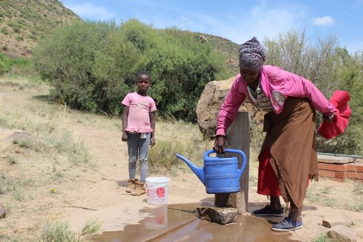 A young girl and her mother fetch water from the community tap. 