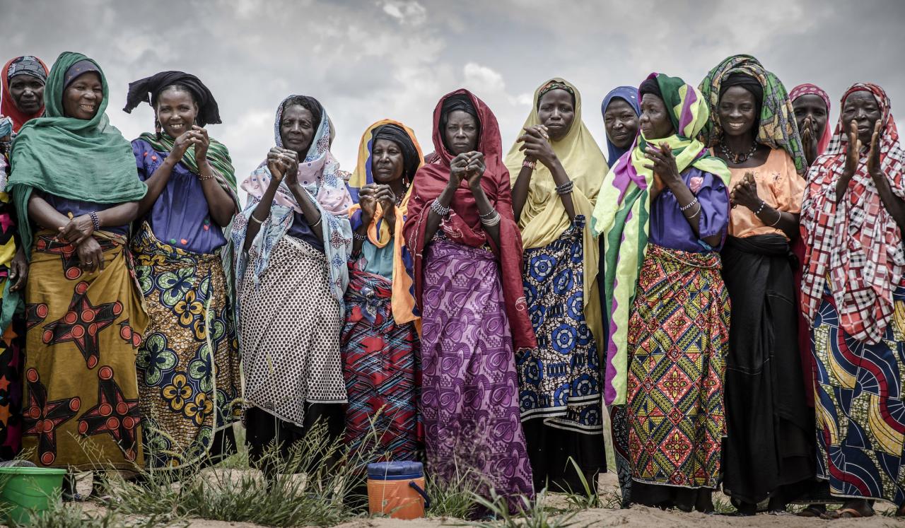 Doce mujeres se colocan una al lado de la otra mientras sonríen a la cámara.