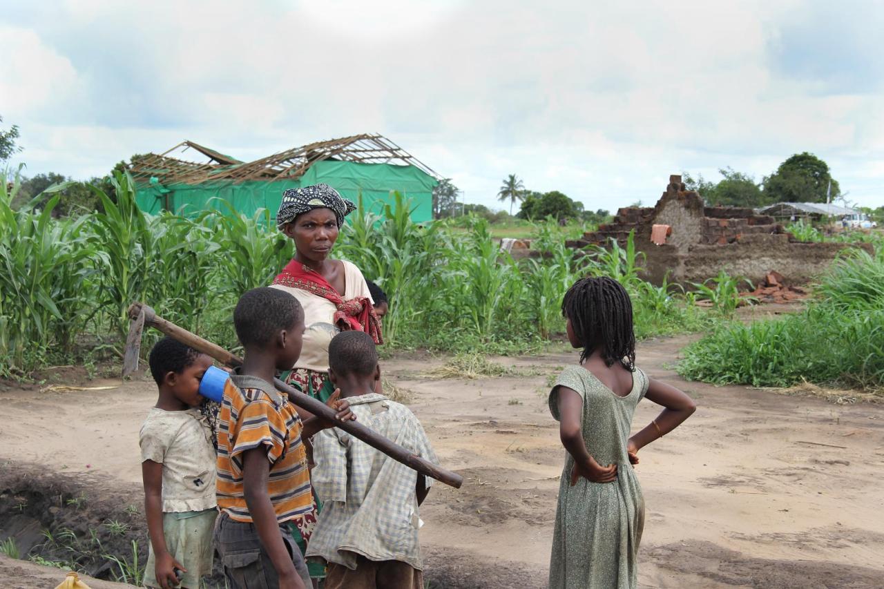 A mother with her children stand outside by their fields after Cycone Eloise.