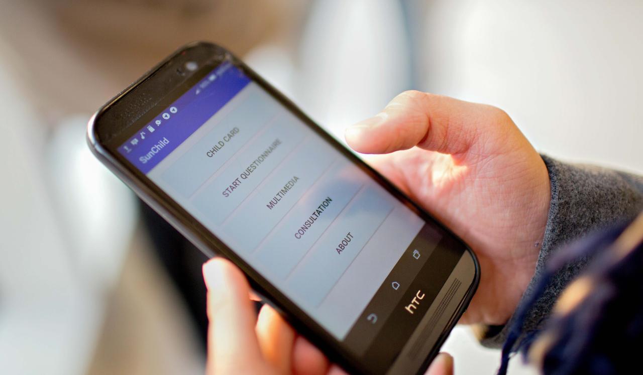 A close-up of a girl's hand holding a mobile phone. The screen displays the SunChild app features.