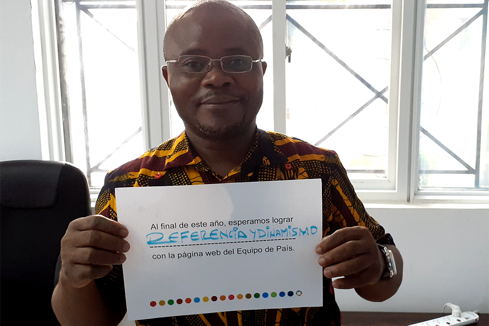 Un hombre con una media sonrisa, que transmite orgullo, sostiene un letrero sobre los objetivos colectivos anuales del equipo de la ONU en el país respecto al nuevo sitio web. "Al final del año, esperamos lograr referencia y dinamismo", destaca el letrero en español.