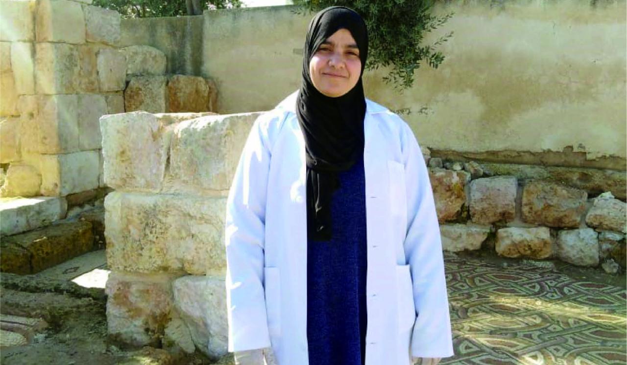 Soheir stands in a lab coat outside. 