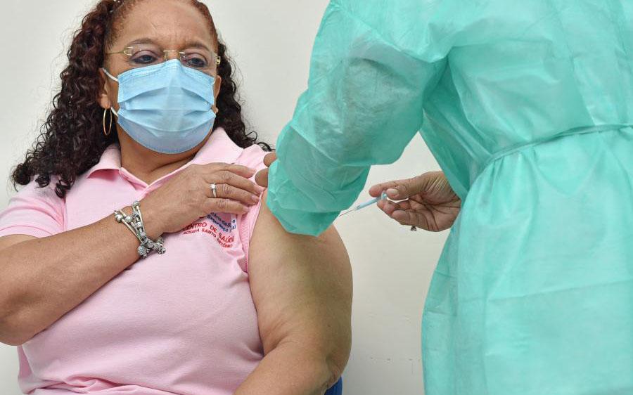 Nurse, Helga Fontes, rolls up her sleeve as a healthcare worker injects her with the COVID-19 vaccine.