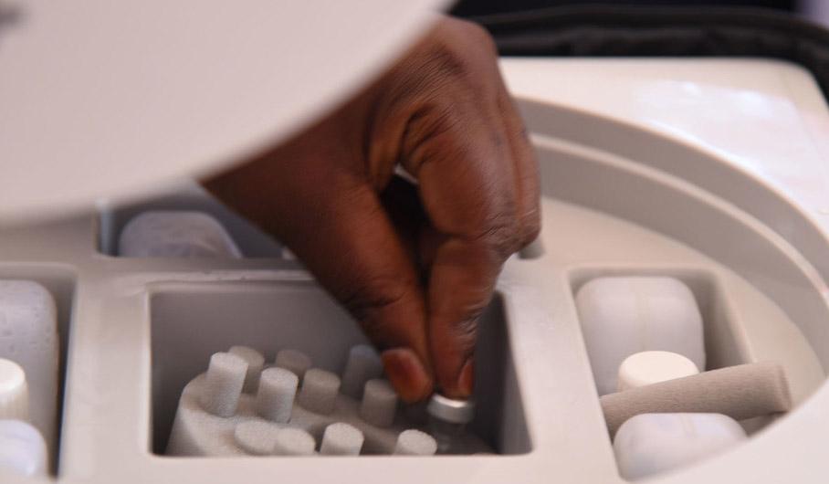A hand is picking up a vaccine. 