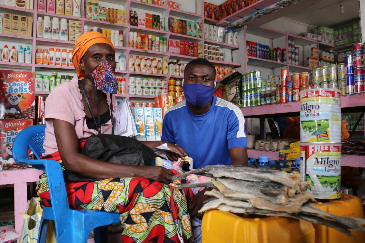 A woman and man wearing face mask sit inside their local market.