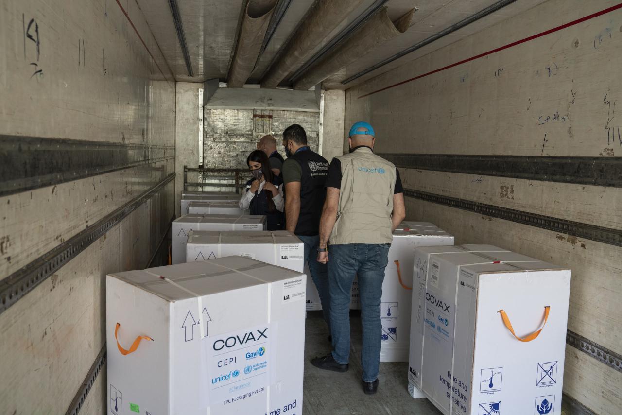 UN country team personnel inspect a COVAX vaccine shipment in a refrigerated truck that has arrived in Syria