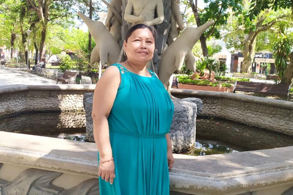 Una mujer con un vestido azul marino se encuentra frente a una fuente.