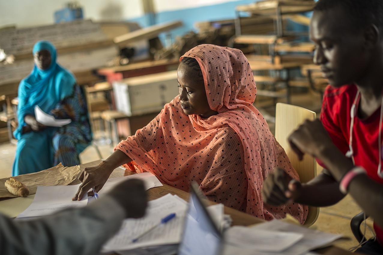 Four people fill out paperwork together at desks. 