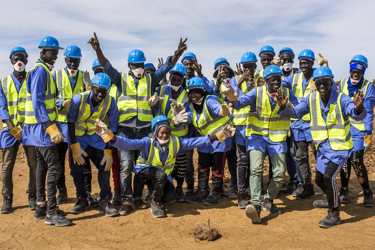 A group of construction workers smile widely at the camera. 