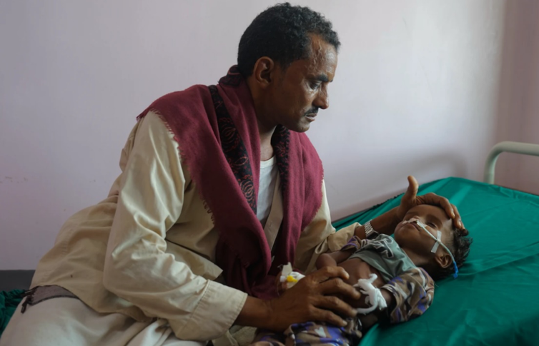 Un hombre mira a su sobrino bebé en una cama de hospital.
