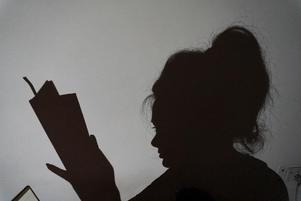 A silouhette of a woman reading a book.