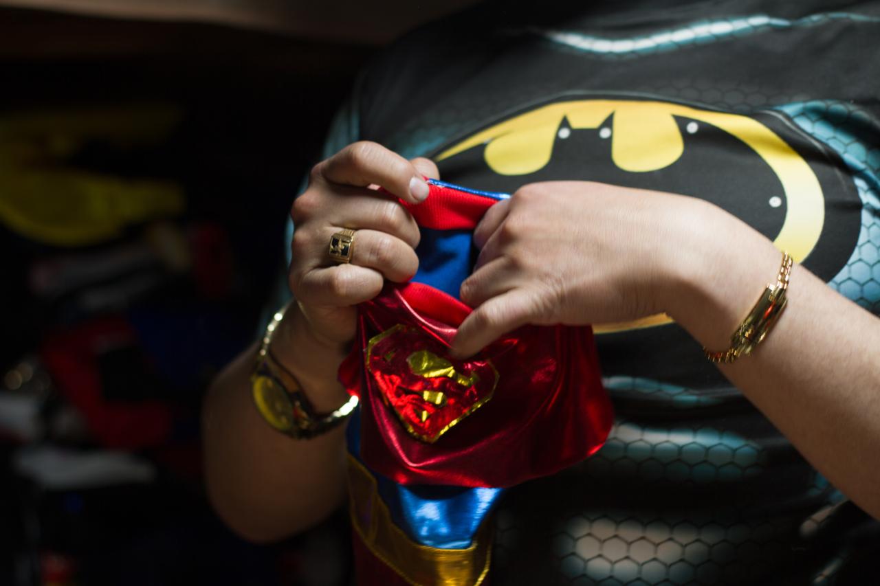 Close-up of two hands holding a superhero costume for a small dog.