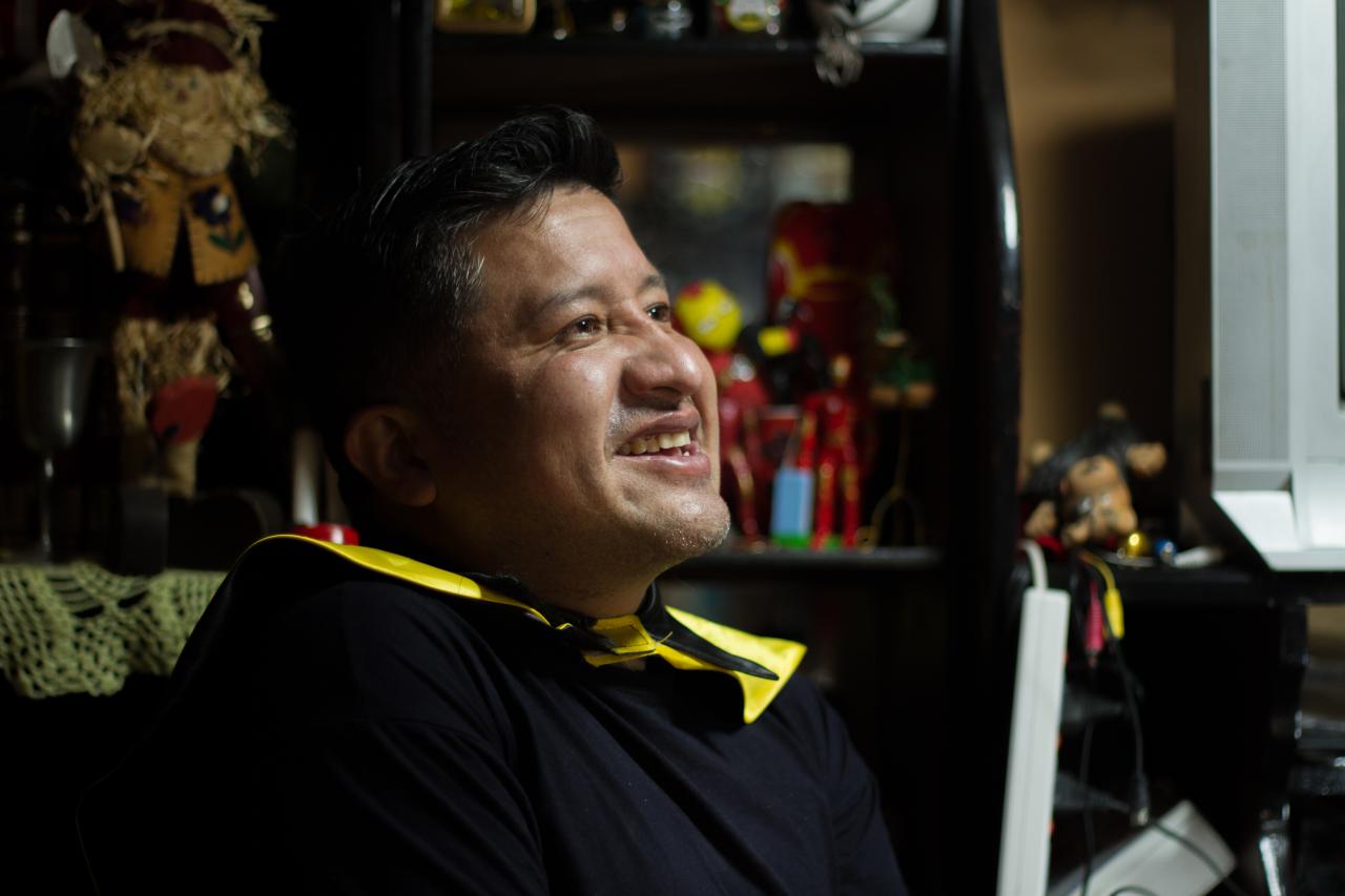 Close-up profile shot of a man smiling while looking straight ahead.