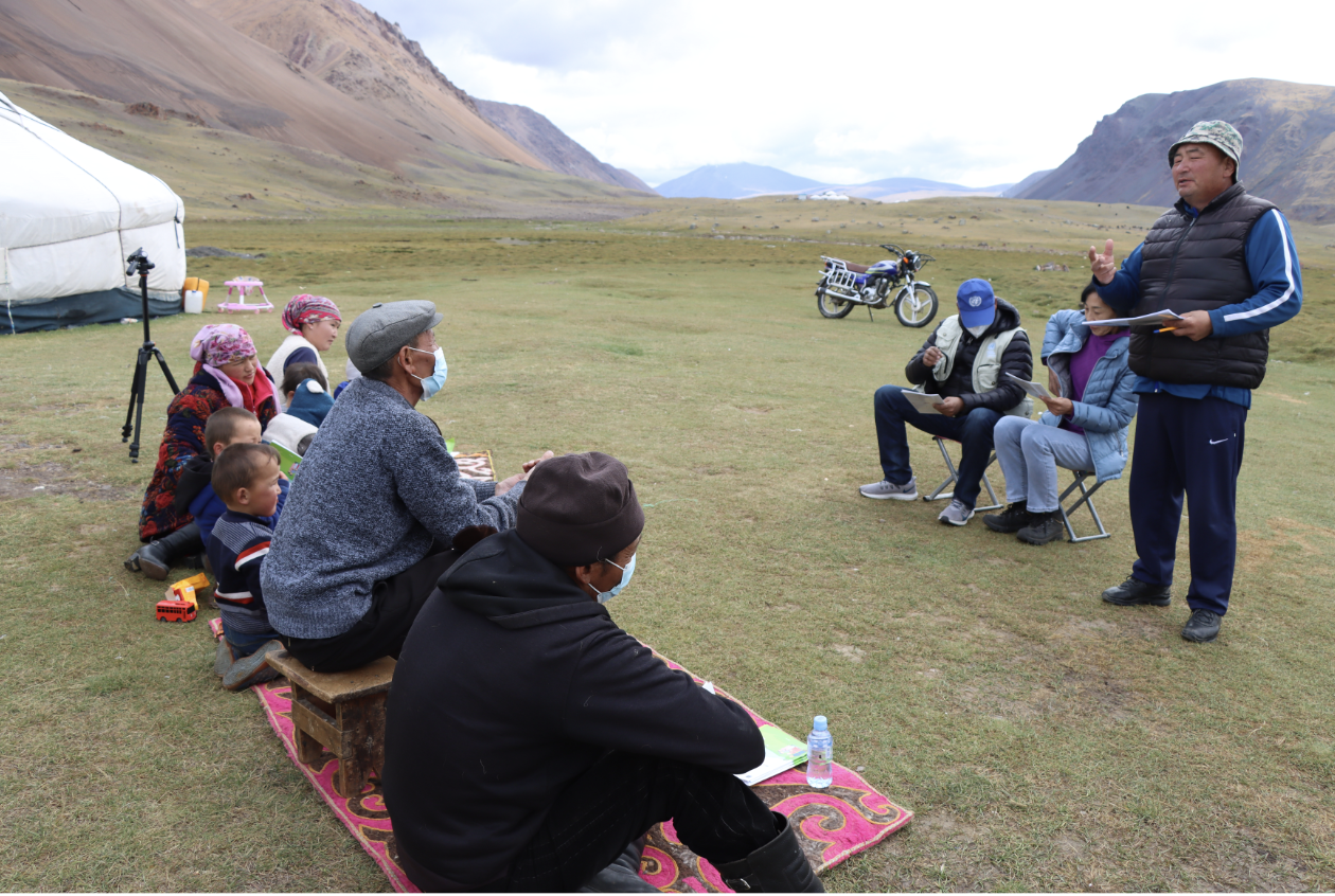 Man speaks to people sitting down on the grass 