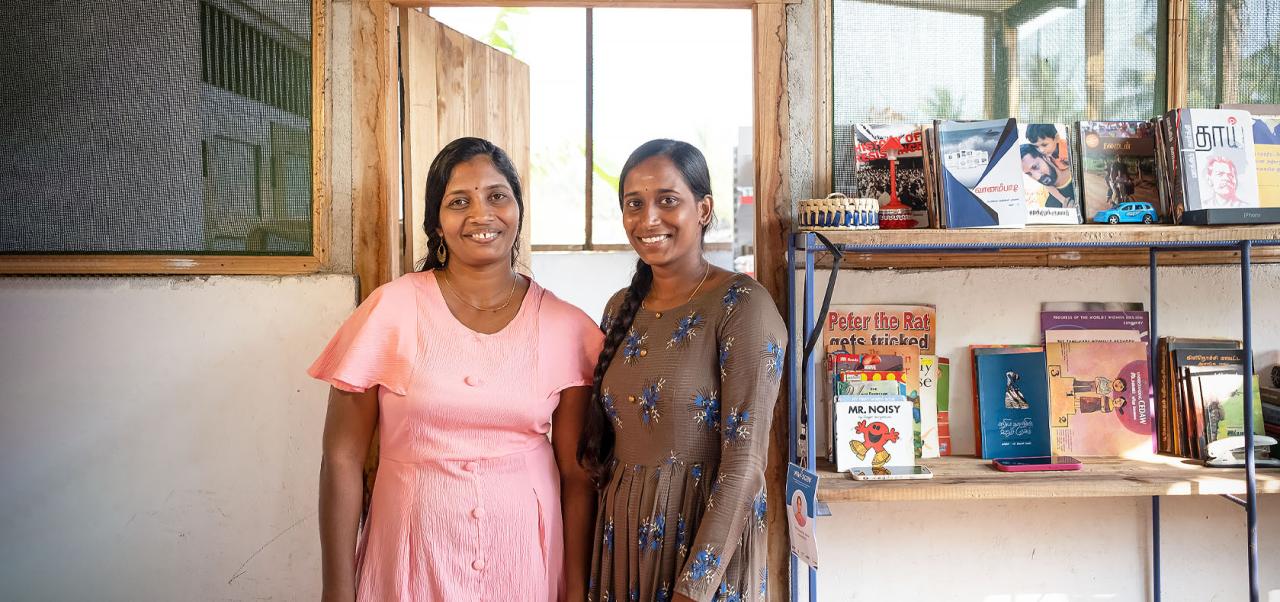 Two women stand in front of some of their merchandise in Sri Lanka.