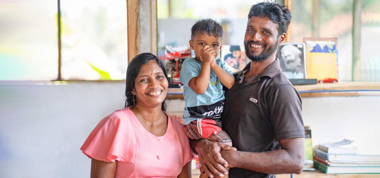 Amother and father with their young son smile for the camera.