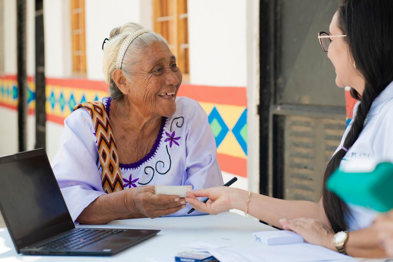 Rosalina Fuenmayor (74), one of the weavers of the yarn cone bank receives his debit card from Banco Plaza, during a special account opening brigade conducted in Paraguaipoa.