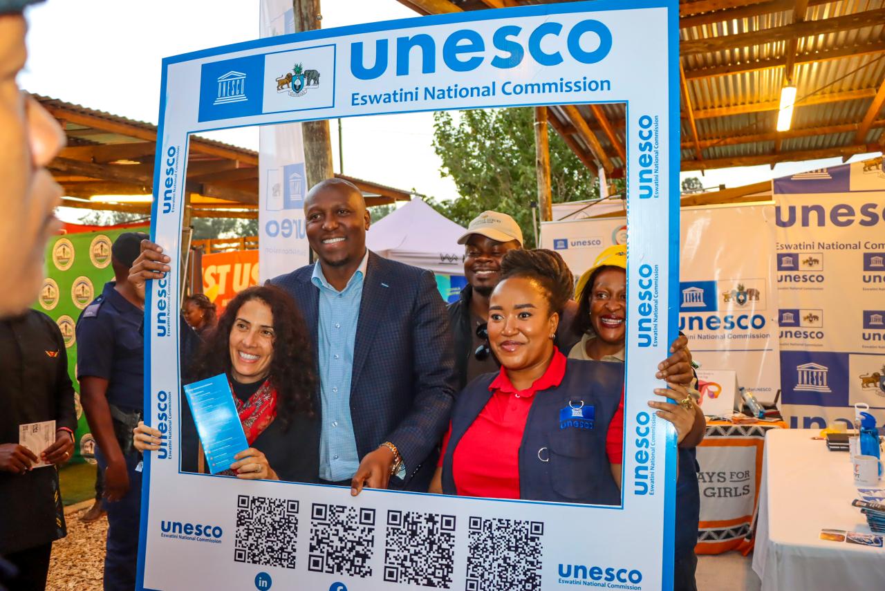 Three people are posing in front of a photo frame