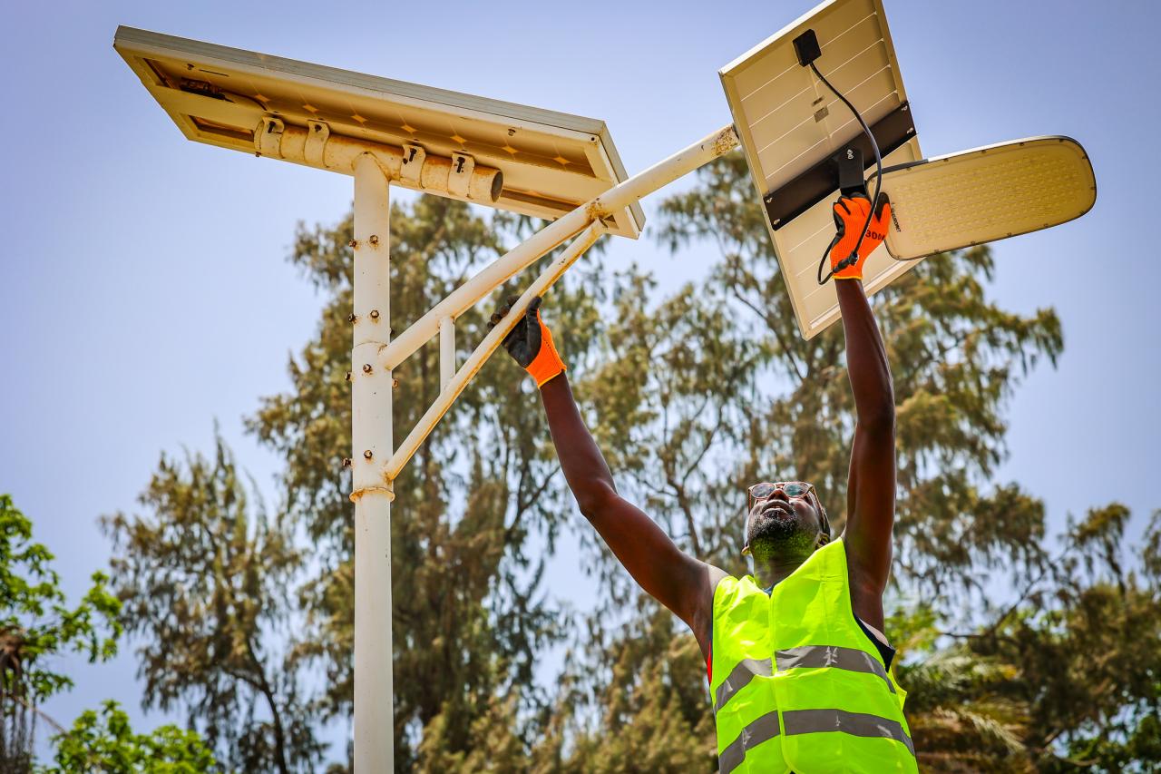 A man erects a pole with solar panels