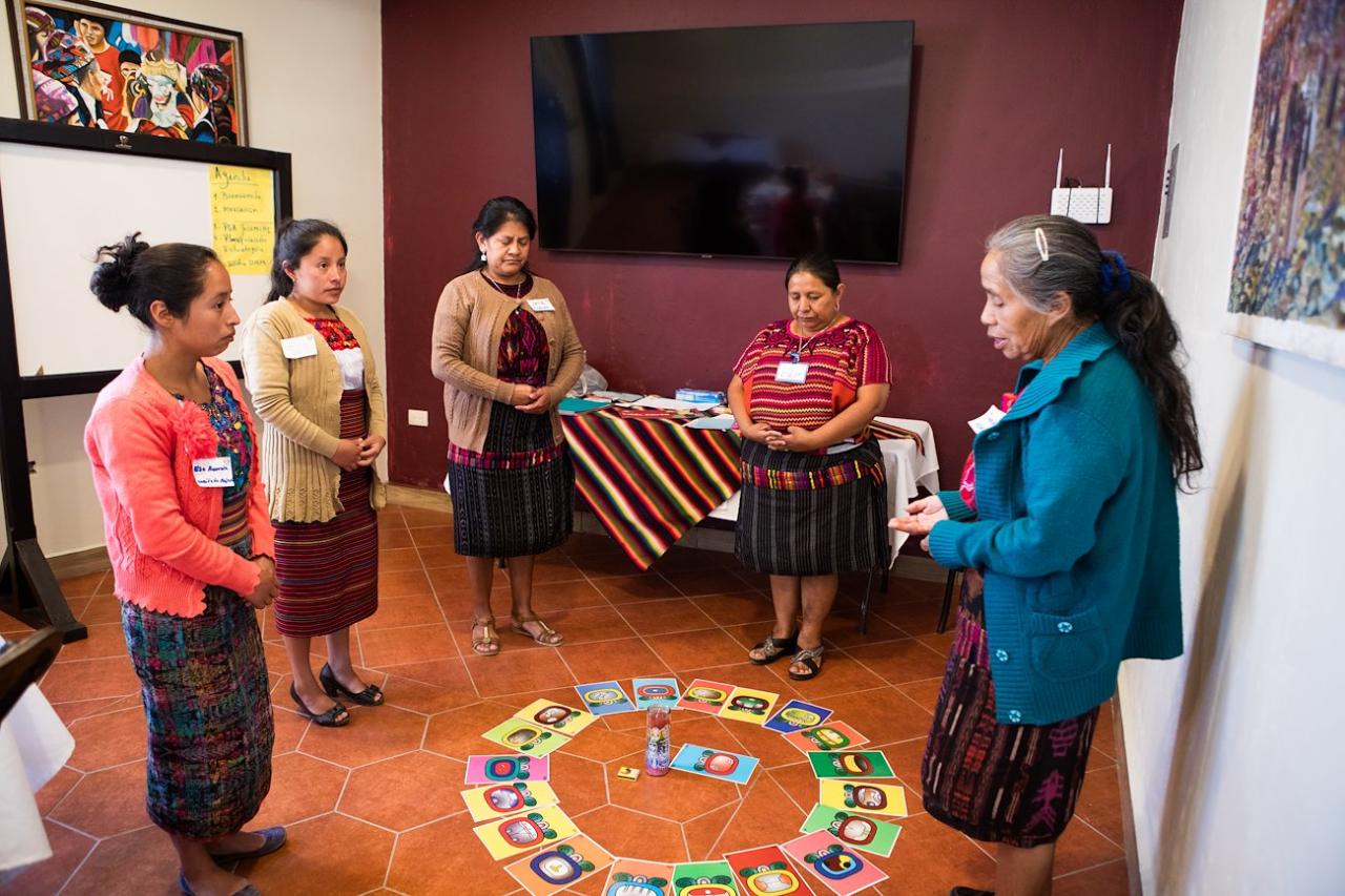 A group of women in a circle engaging in an activity 