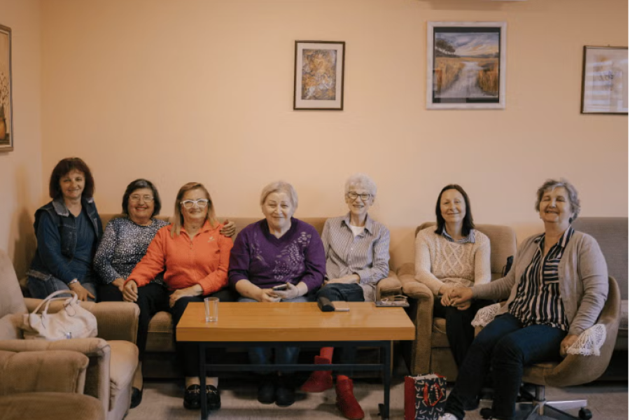 A group of pensioners are sitting together in a sofa.