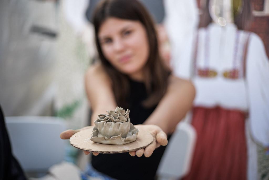A young woman displays a pottery item she made.