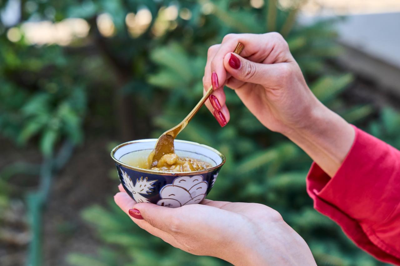 A woman stirs some fresh honey in a small bowl.