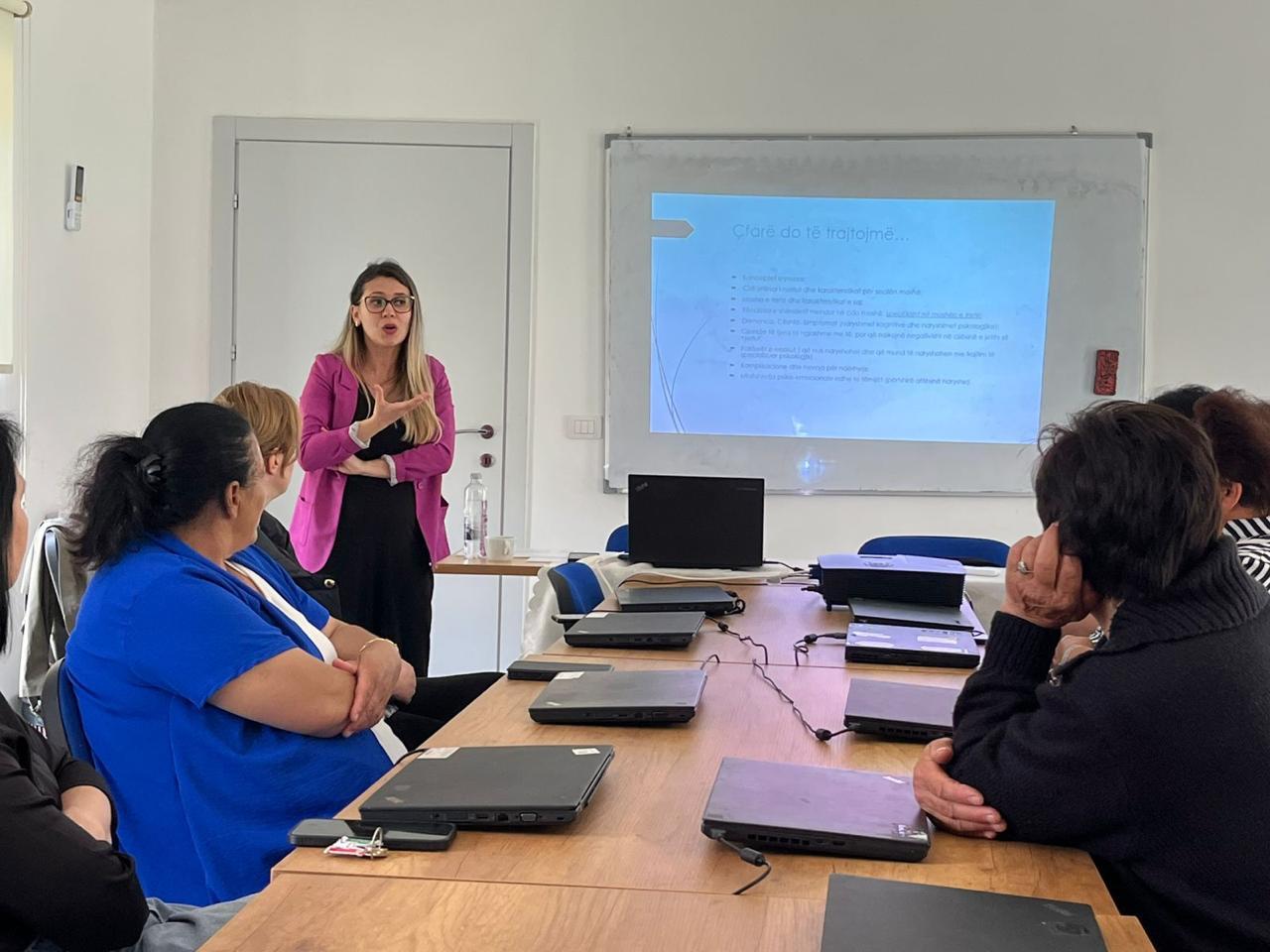 A woman in Albania gives a training session in front of other women in a small room.
